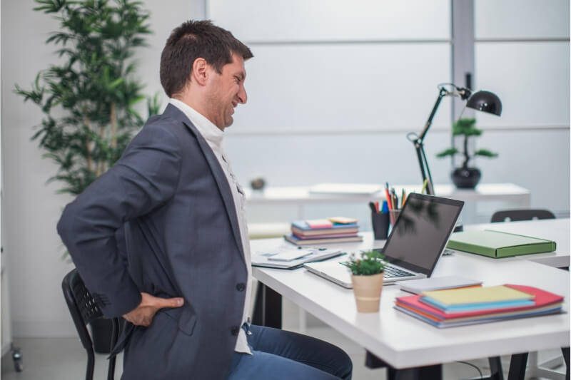An image of a person suffering from a lower back pain at office