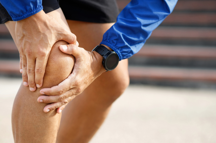 Holding his knee to relieve pressure from a running knee injury
